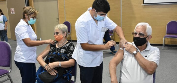 alt="dos personas son vacunados por un hombre y por un mujer"