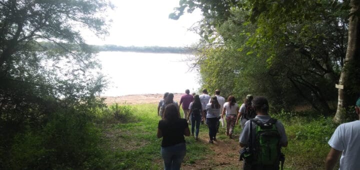 alt="senderistas recorren la selva en galería a orillas de un río"