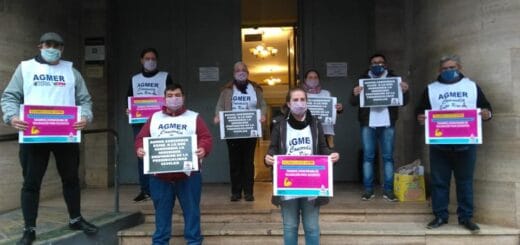 alt="en la imagen, integrantes de agmer sostienen carteles en el acceso a la municipalidad de concordia"