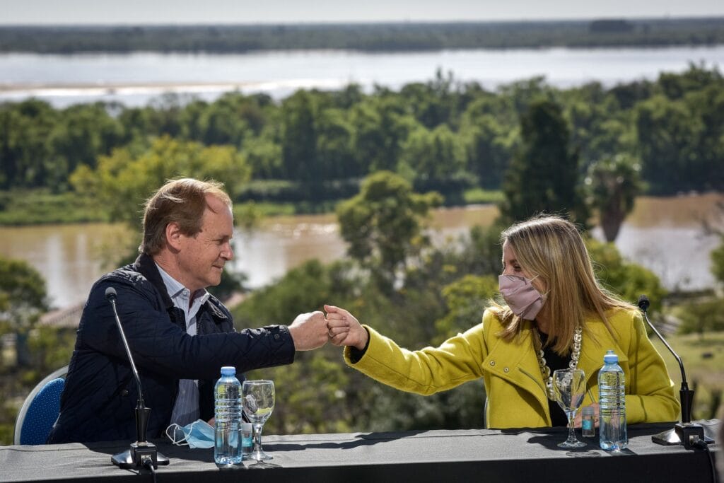 alt="en la fotografía, un hombre y una mujer se saludan chocando sus puños; en el fondo de la fotografía puede verse un brazo del río Paraná"
