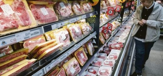 alt="en la imagen se ve a una mujer eligiendo cortes de carne vacuna en una góndola de supermercado"
