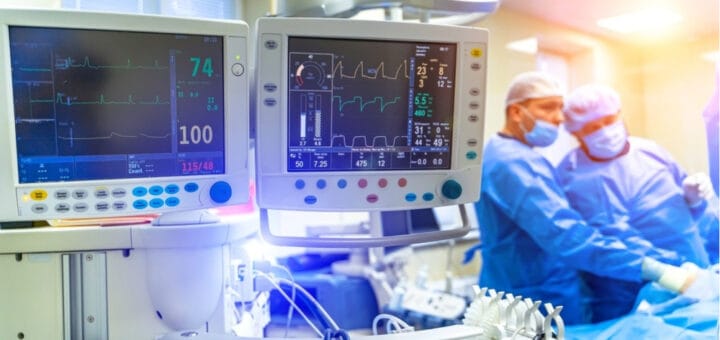 alt="equipamiento para monitorear los signos vitales y dos profesionales de la salud en una sala de terapia intensiva"