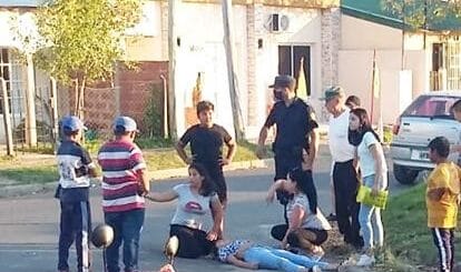 alt="en la imagen puede verse a varias personas, entre ellas dos policías, que auxilian a una mujer tendida sobre el pavimento de una calle"