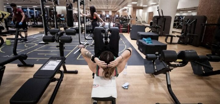 alt="en la fotografía puede verse el interior de un gimnasio, con personas realizando ejercicios"