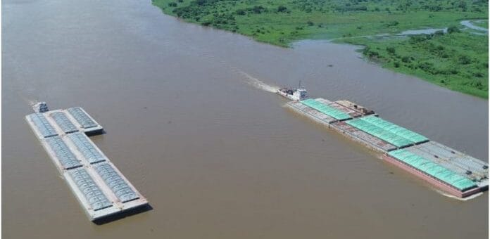 alt="dos convoyes de barcazas avanzan por un río"