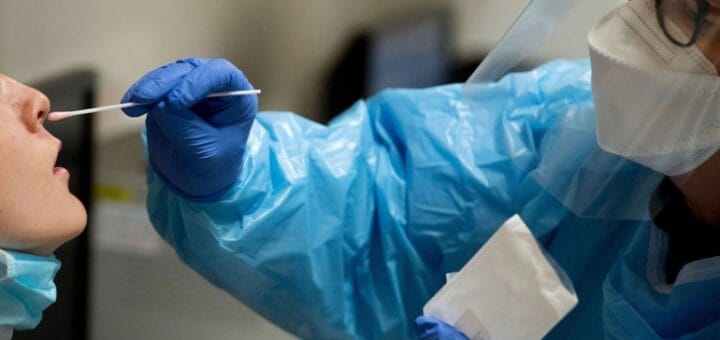 alt="en esta imagen puede verse a una persona realizando un hisopado a otra"