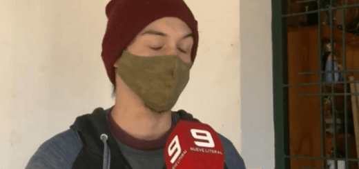 alt="en la imagen, un joven con barbijo y pasamontañas, delante de él un micrófono"