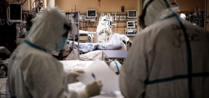 alt="en la imagen, una sala de terapia intensiva con un paciente en una cama y tres integrantes del equipo de sanitario"