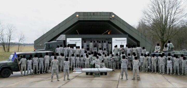 alt="en esta imagen pueden verse a soldados norteamericanos posando con una bomba nuclear en una base aérea"