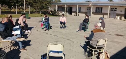 alt="en la imagen pueden verse a docentes sentados en el patio de una escuela"