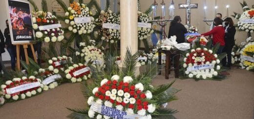 alt="en la imagen pueden verse coronas fúnebres, un ataúd y gente dando un último adiós"