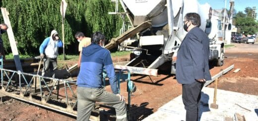 alt="en la foto pueden verse trabajos de hormigonado en la vía pública, obreros trabajando, camión volcador y hombre con traje"