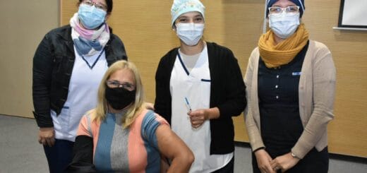 alt="en esta imagen tres enfermeras posan detrás de una docente que concurrió a vacunarse"