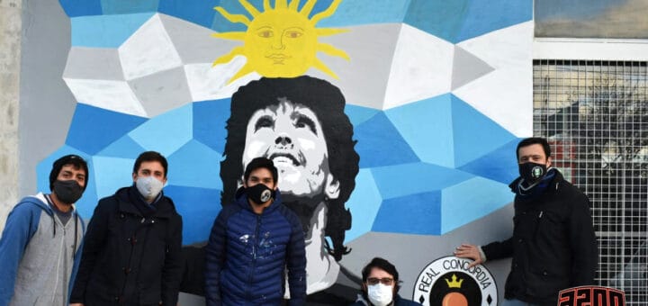 alt="en la imagen, el mural de diego maradona, junto al sus autores y otras personas"