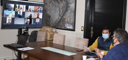 alt="un hombre y una mujer participan de una videoconferencia, en una pantalla se observa a los participantes virtuales"