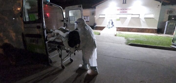 alt="en la imagen, un paciente es ingresado a una ambulancia, detrás un centro sanitario"