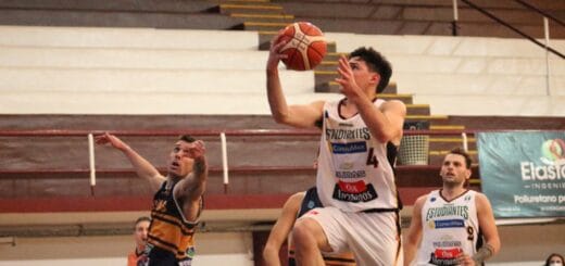 alt="en la imagen un jugador de básquet busca encestar el balón, otros lo corren"