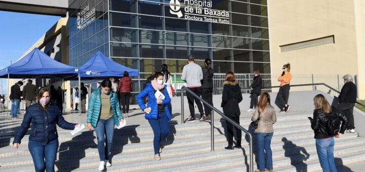 alt="en la imagen puede verse, a la derecha, personas esperan en las escalinatas su turno para ingresar al hospital de la baxada: a la izquierda, otras personas se retiran del mismo hospital"