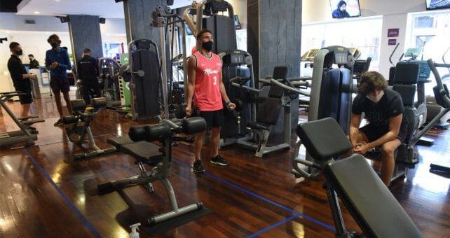 alt="en la imagen puede verse a personas realizando actividad física en un gimnasio"