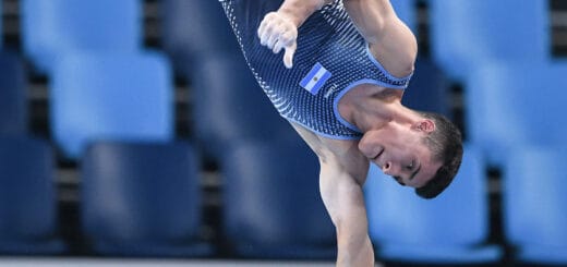 alt="en la imagen, un atleta realizando su rutina de gimnasia artística"