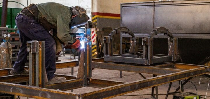 alt="en la imagen puede verse a un hombre soldando un cuadro de metal"