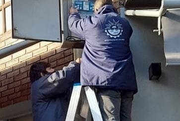 alt="dos trabajadores municipales trabajan en el controlador de un semáforo"