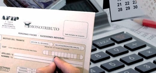 alt="en la imagen puede verse un teclado de ordenador y un formulario de inscripción al monotributo sostenido por una mano"