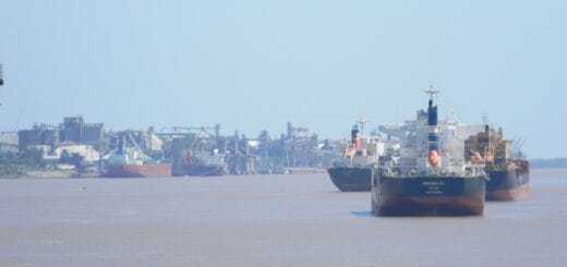 alt="en la imagen pueden verse tres barcos navegando y uno en un puerto sobre un río"