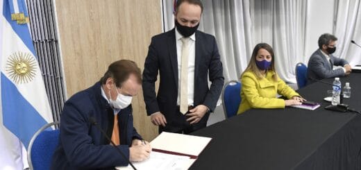 alt="en la imagen, el gobernador bordet firma convenios para realizar obras, lo acompañan tres personas"