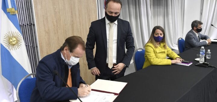 alt="en la imagen, el gobernador bordet firma convenios para realizar obras, lo acompañan tres personas"