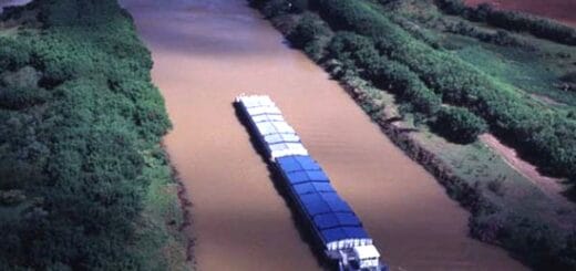 alt="en la imagen puede verse a un remolcador empujando barcazas en un río"