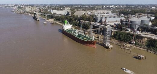alt="en la imagen puede verse un puerto fluvial con barcos cargando cereal y algunas lanchas navegando"