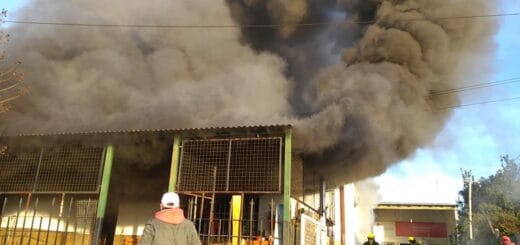 alt="en la imagen puede verse humo saliendo del interior de una vivienda, un hombre observa"