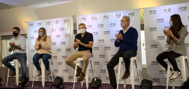 aalt="en la imagen puede verse a tres hombres y dos mujeres sentados en bancos"