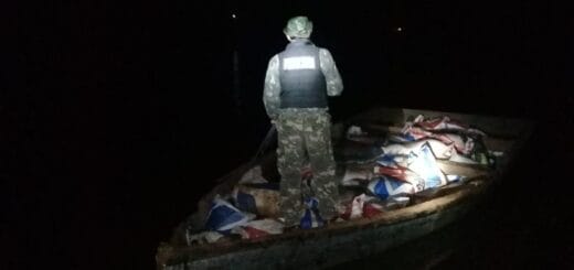 alt="en la imagen puede verse a un integrante de la Prefectura argentina subido a un bote donde hay numerosos bultos"