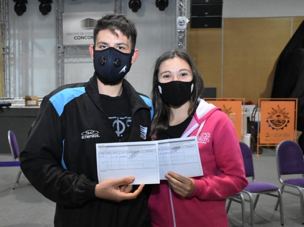 alt="en la imagen puede verse a una pareja que exhibe su certificado de vacunación"