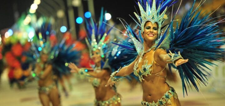 alt="en la imagen puede verse a una joven mujer con adornos de plumas en un desfile de carnaval"