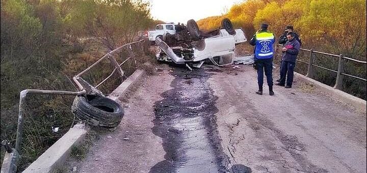 alt="en la imagen una camioneta volcada en un camino rural cerca de una alcantarilla"