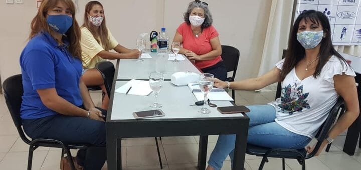 alt="en la imagen pueden verse a cuatro mujeres sentadas alrededor de una mesa"