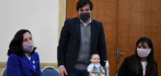 alt="Sentado, sobre un escritorio, uno de los muñecos inclusivos OLI"