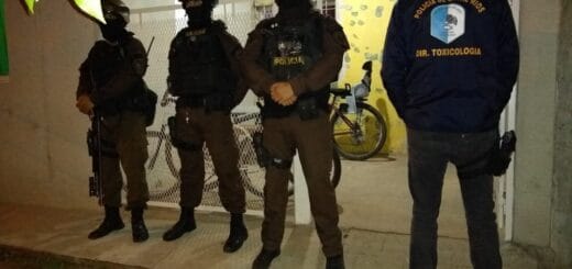alt="en la imagen puede verse a cuatro policías apostados en el frente de una vivienda en San Salvador"