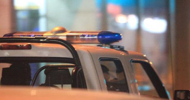 alt="en la imagen puede verse parcialmente una patrulla policial con las luces en el techo de la cabina"