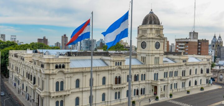 alt="banderas de entre ríos y argentina flamean frente a la casa de gobierno en Paraná"