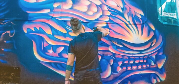 alt="un hombre pintando un grafitti en un tren"