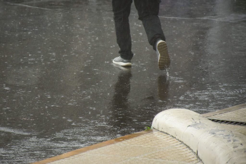 alt="Mantenete informado sobre las alertas por tormentas en Entre Ríos. En la nota gráfica se observan los pies de una persona que cruza la calle en un día de mucha lluvia"