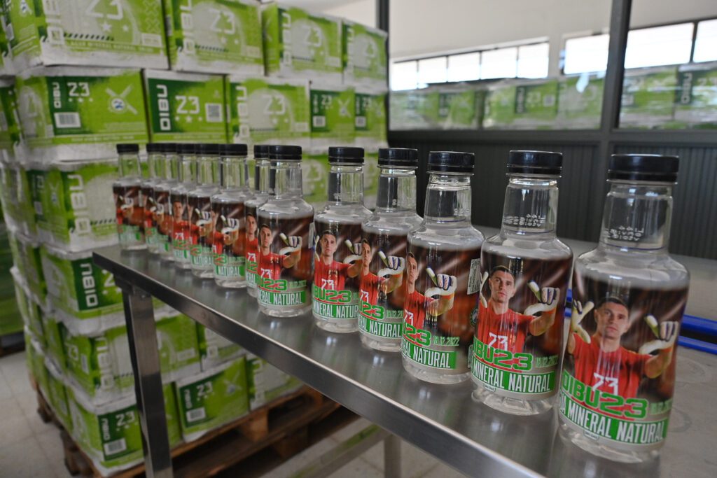 alt="botellas de agua mineral etiquetadas con la imagen del Dibu Martinez, en Puerto Yeruá. Su distribución se verá favorecida por obras a realizarse en el acceso a la localidad"