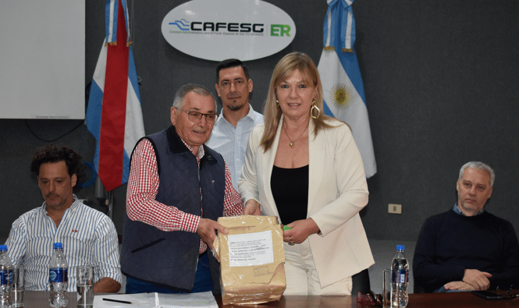 alt="el presidente de CAFESG, Carlos Cecco, sostiene uno de los sobres con ofertas para la refacción de la cocina del Hospital San José de Federación"