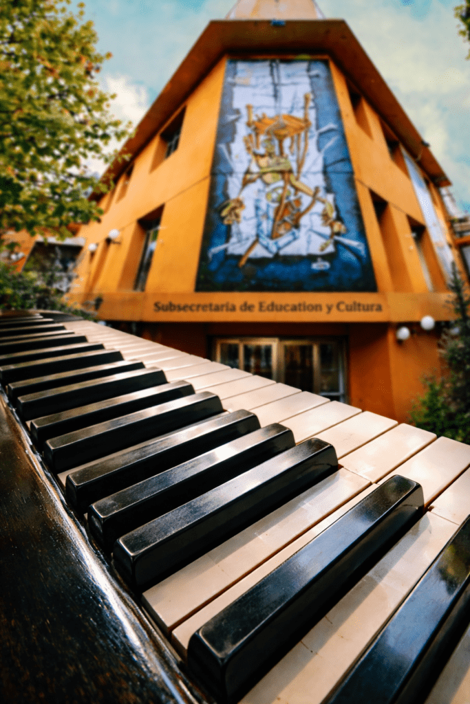 alt="Teclado de piano utilizado en las clases de música en Concordia y edificio de la Subsecretaría de Educación y Cultura"
