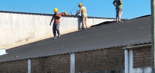 alt="Obreros con cascos amarillos reparando el techo de una escuela, reflejando obras de infraestructura escolar en Concordia"