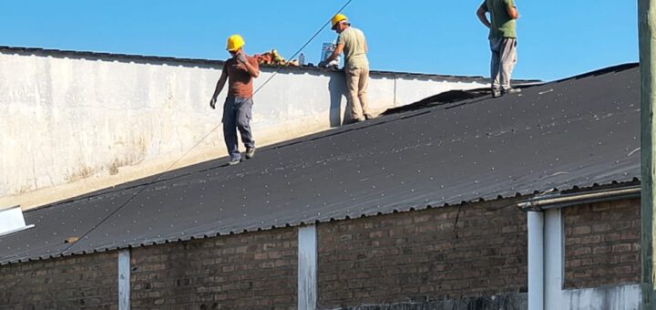 alt="Obreros con cascos amarillos reparando el techo de una escuela, reflejando obras de infraestructura escolar en Concordia"